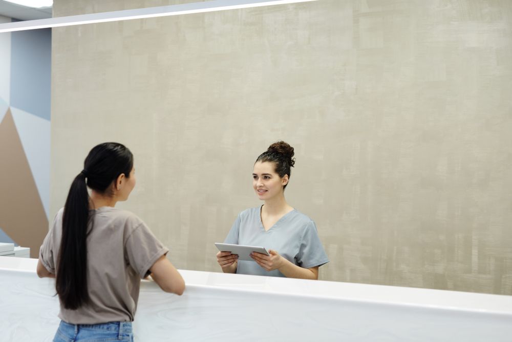 Receptionist assisting a patient with a tablet